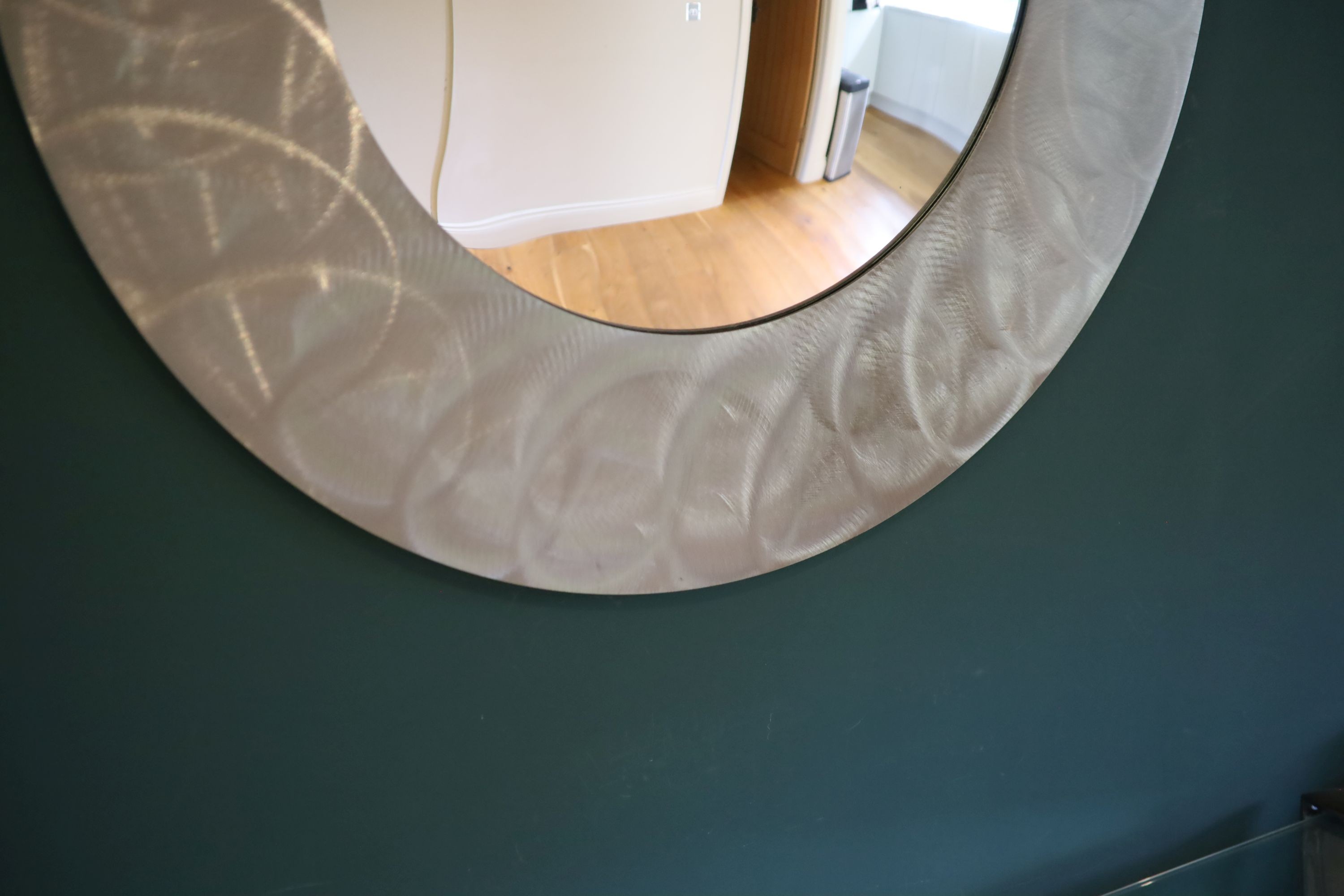 A brushed steel circular wall mirror, 96cm